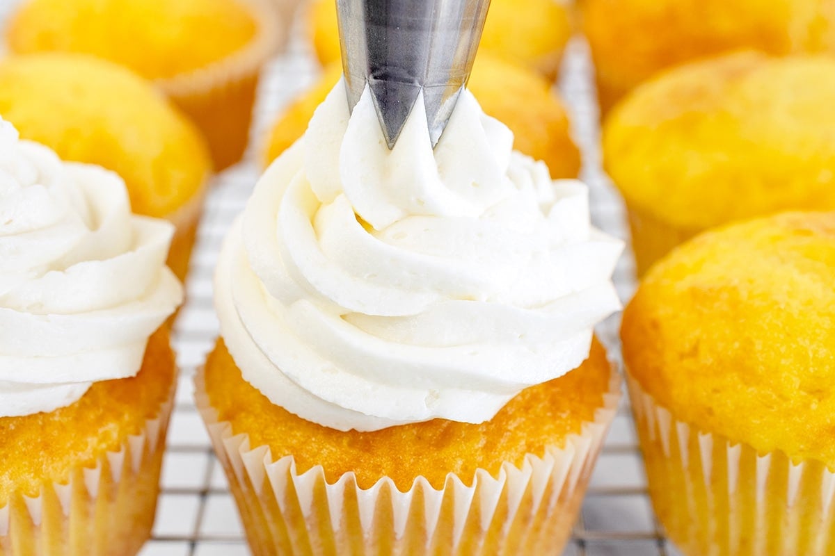 piping buttercream onto cupcake