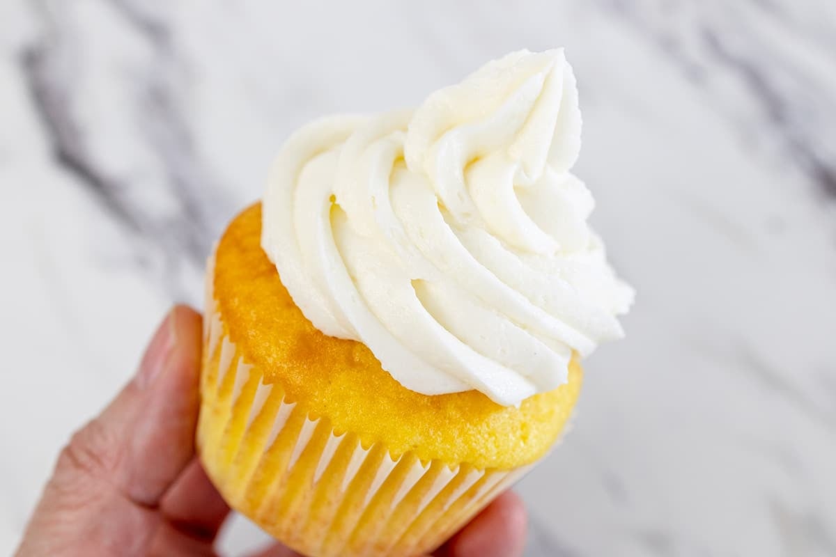 hand holding cupcake with vanilla buttercream