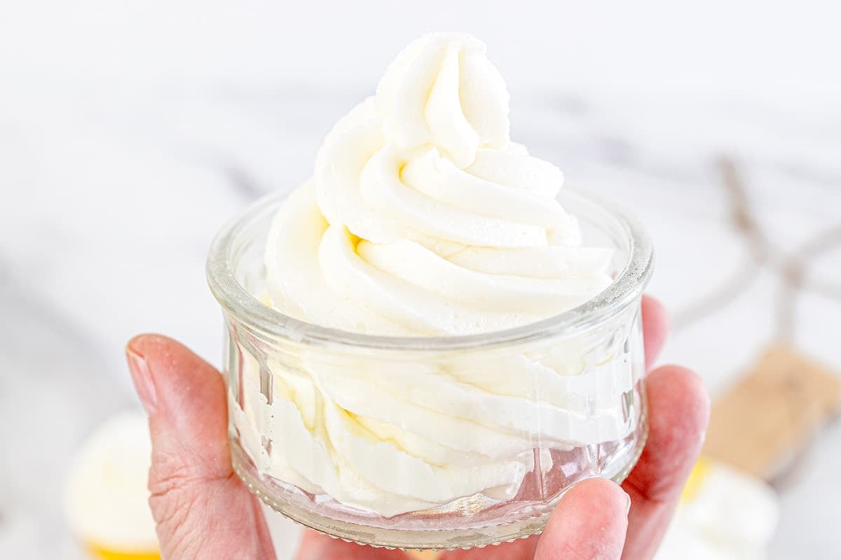 hand holding jar of vanilla buttercream frosting