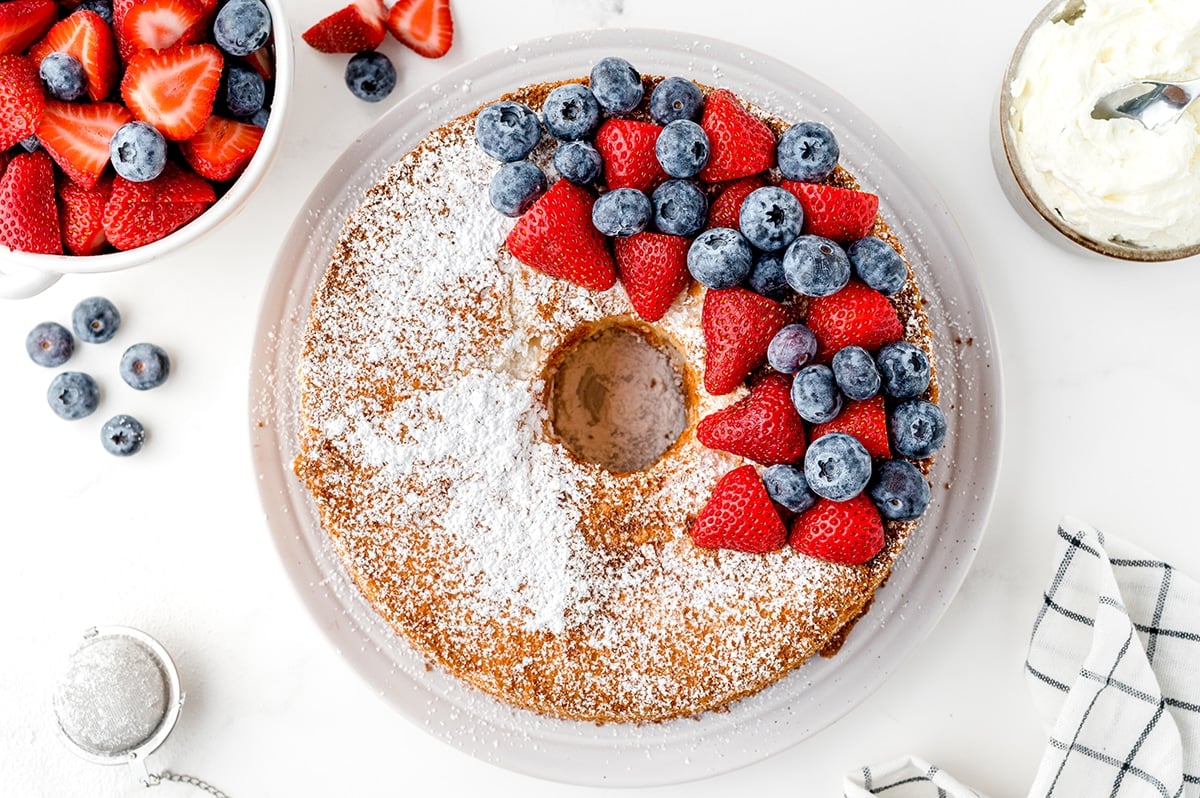 overhead shot of angel food cake topped with berries and powdered sugar