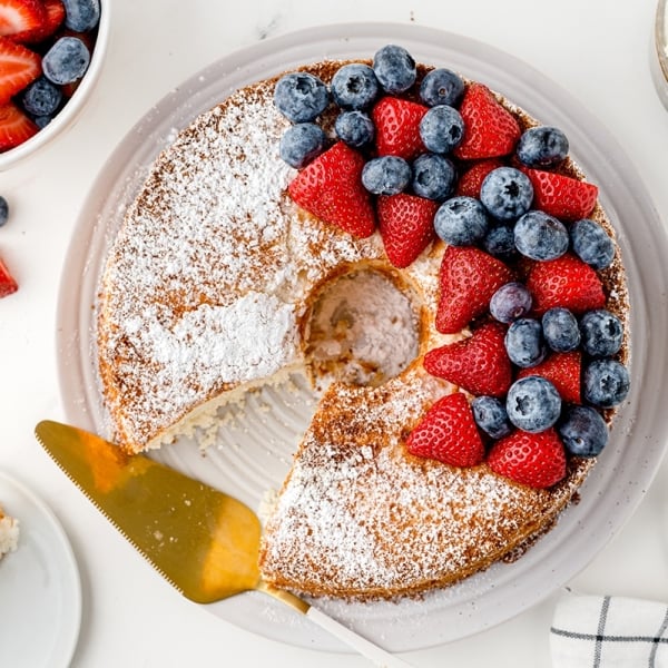 overhead shot of slice taken out of cake topped with berries