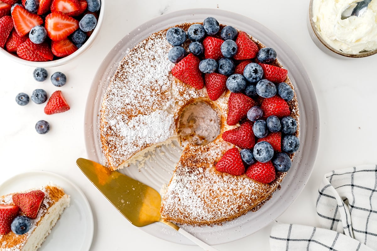 overhead shot of slice taken out of cake topped with berries