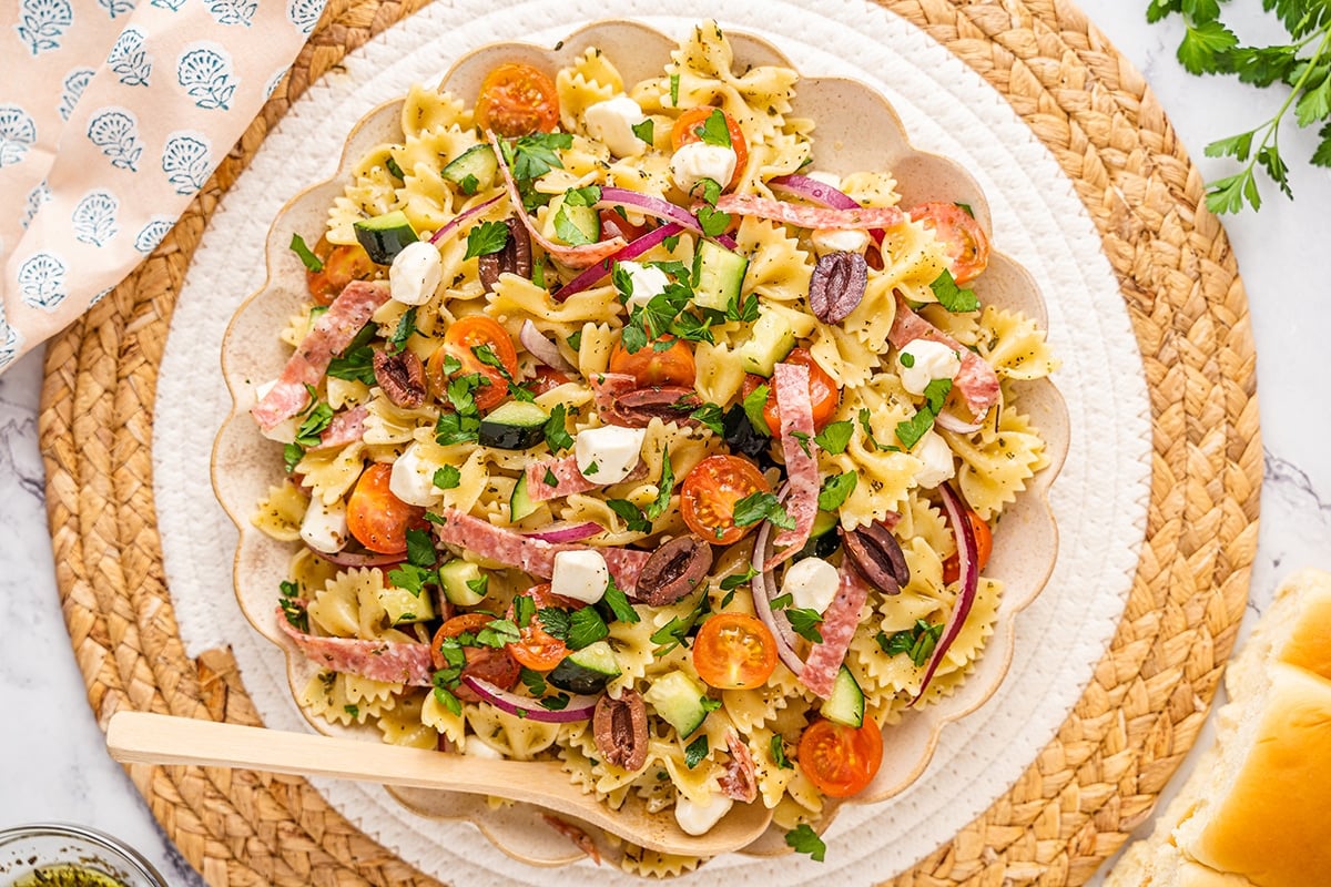 overhead shot of bowl of antipasto pasta salad with wooden spoon