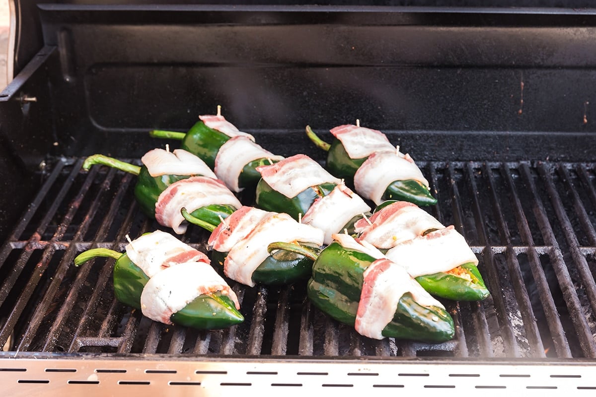 bacon wrapped poblano stuffed peppers on a grill