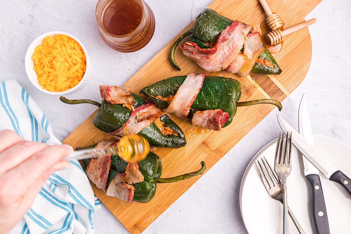 hand drizzling honey on stuffed poblano peppers