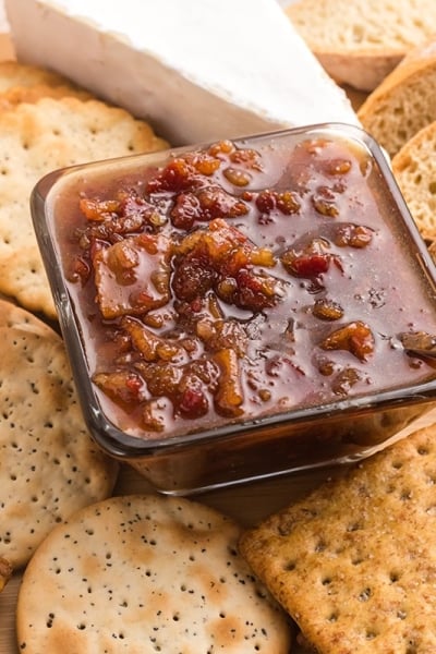 angled shot of bowl of bacon jam on board with breads