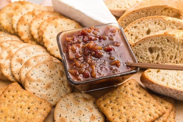 angled shot of bowl of bacon jam on board with breads