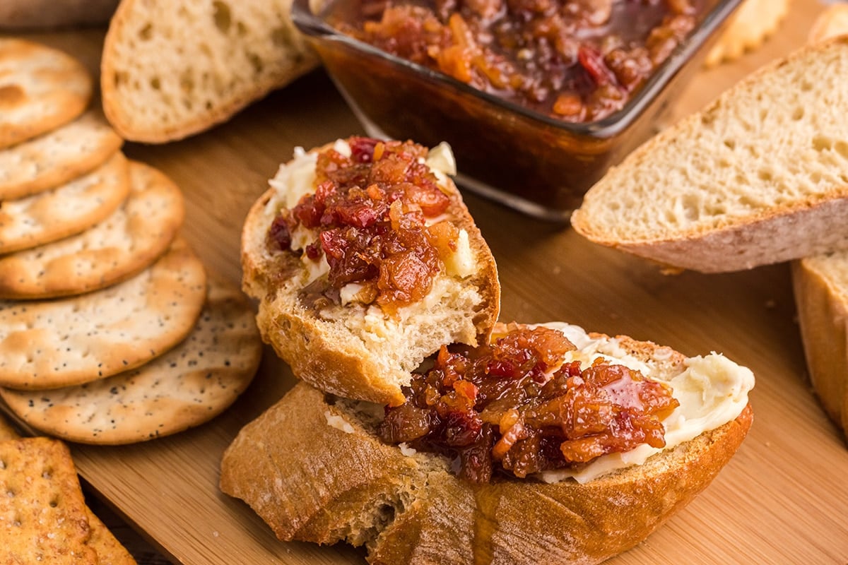 angled shot of bite taken out of bread slice with bacon jam and cheese