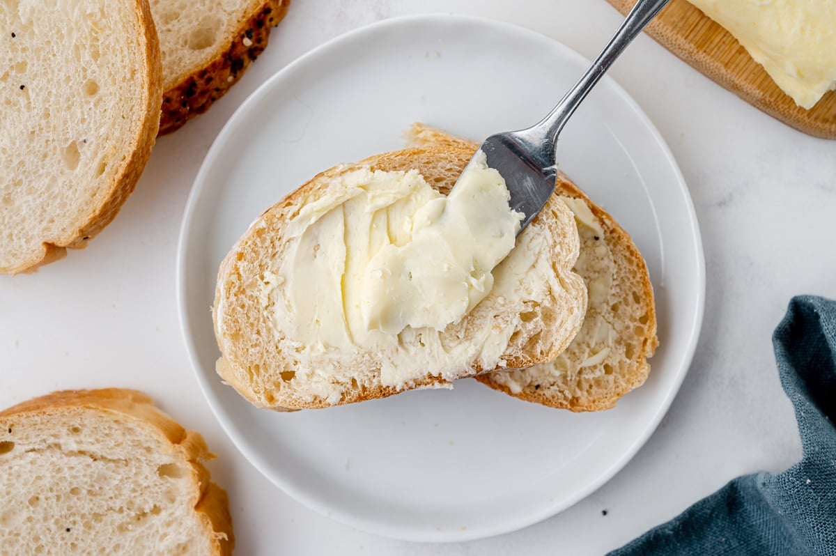 overhead shot knife spreading butter onto slice of bread
