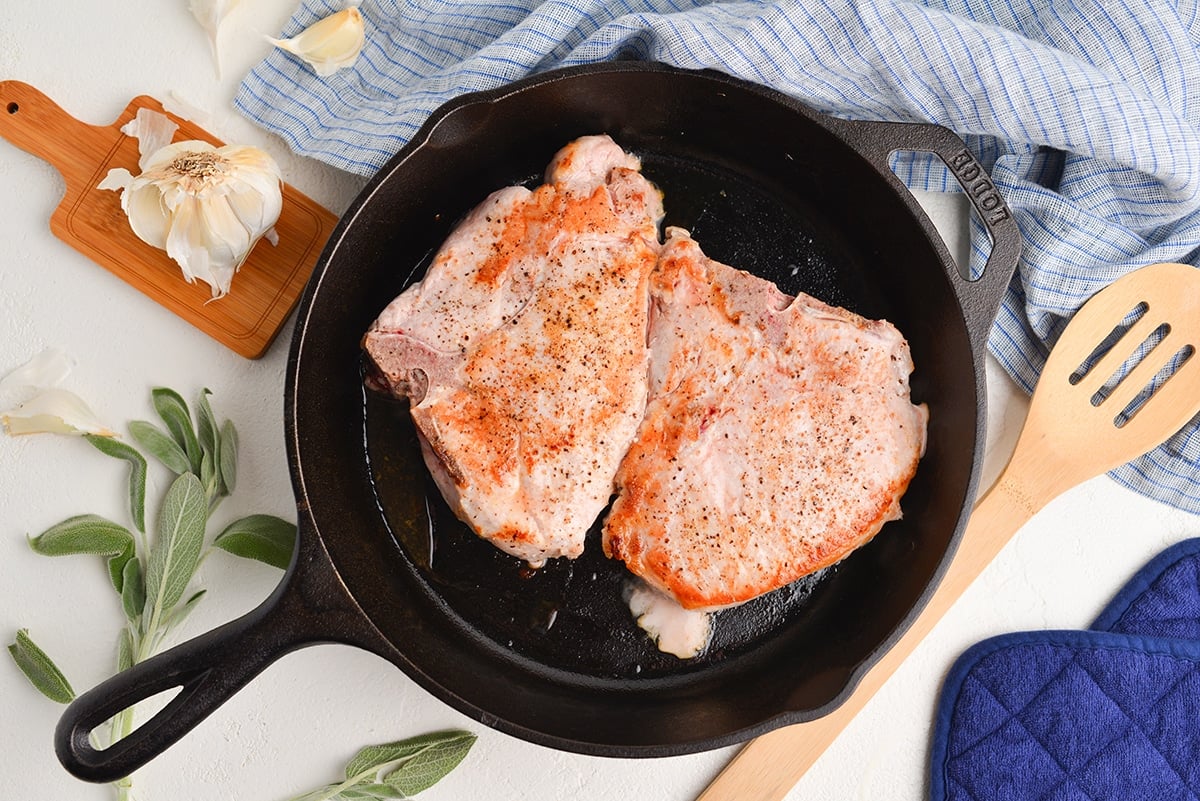 bone-in pork chops browning in a cast iron pan