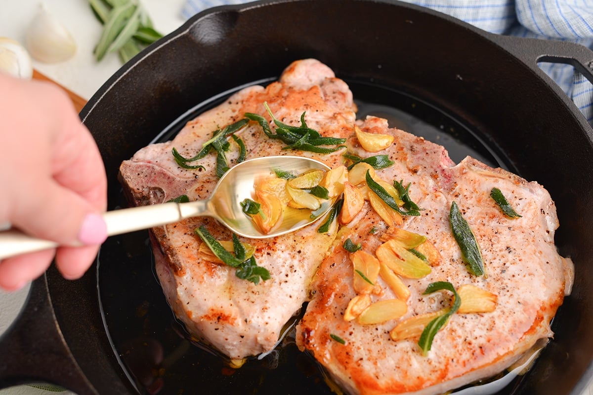 spooning garlic and sage over pork chops