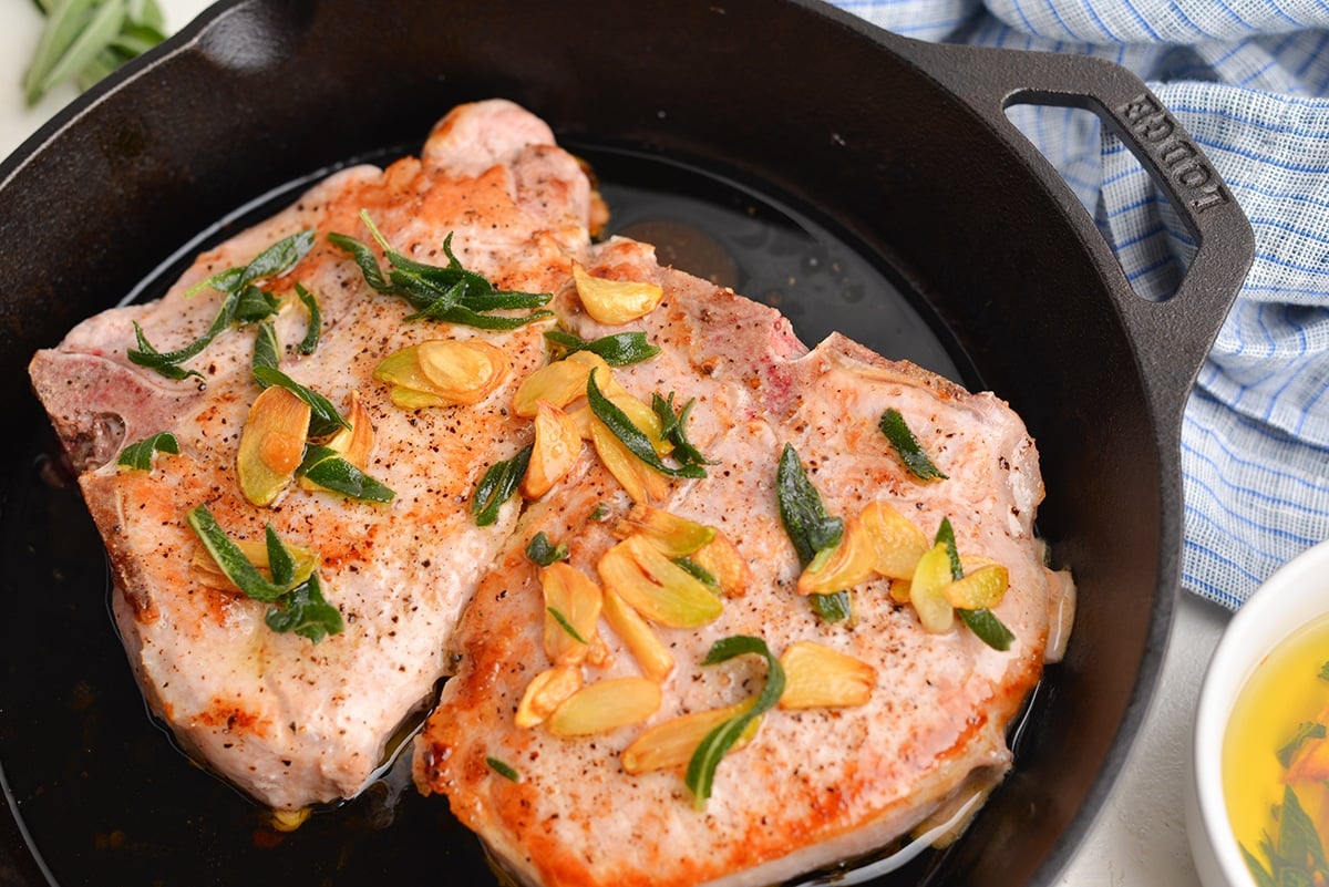 close up angle of pork chops browning in cast iron