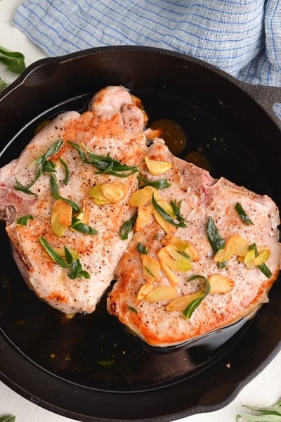 overhead of pork chops in a butter sage sauce