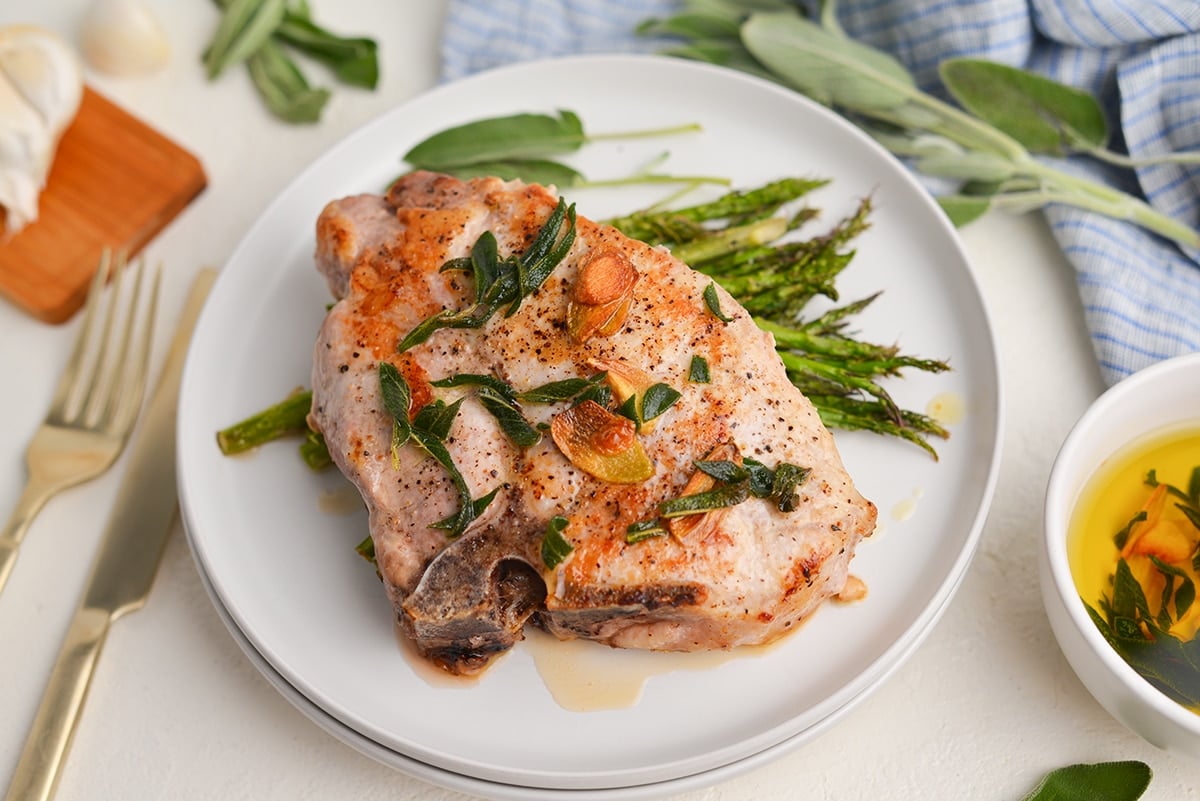 bone-in pork chop with compound butter over roasted asparagus