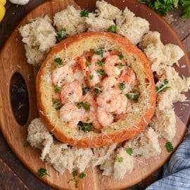 bread bowl filled with creamy shrimp scampi and topped with parmesan cheese and parsley