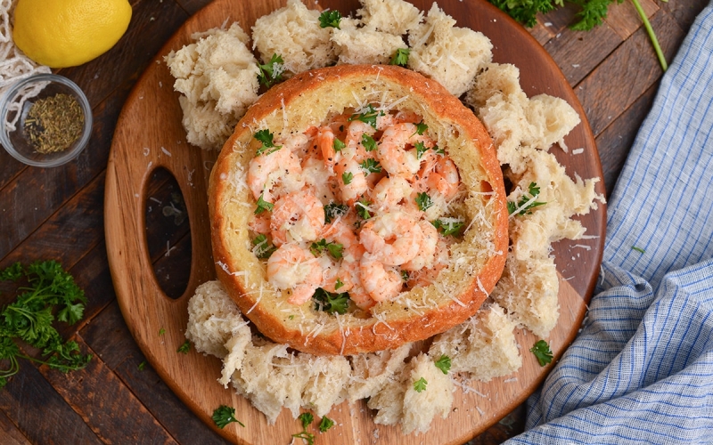 bread bowl filled with creamy shrimp scampi and topped with parmesan cheese and parsley