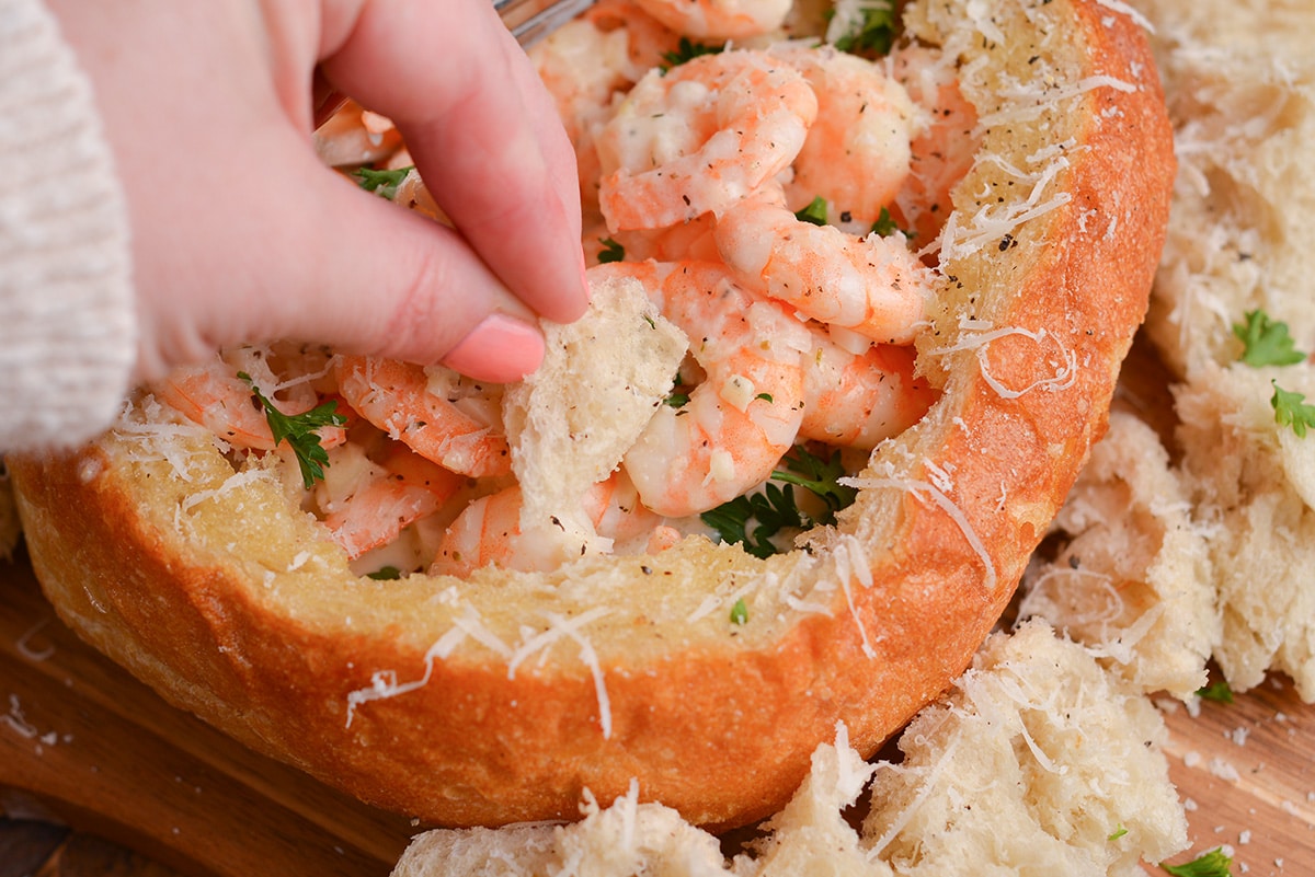 hand dipping bread into a cream sauce