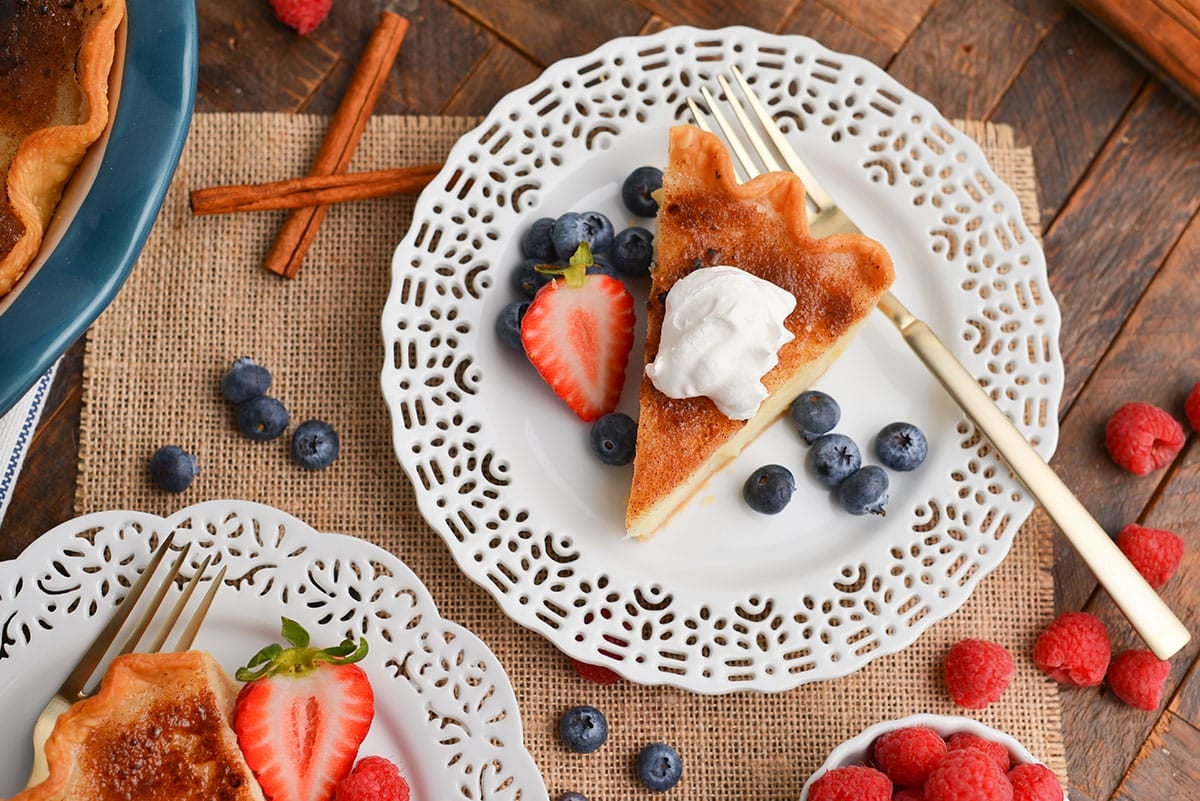 overhead shot of slice of sugar cream pie on plate with whipped cream and berries