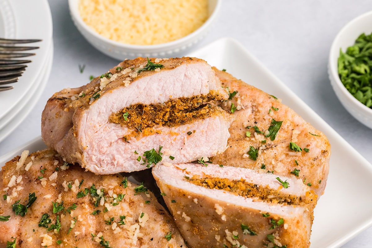 close up shot of tray of grilled stuffed pork chops cut in half