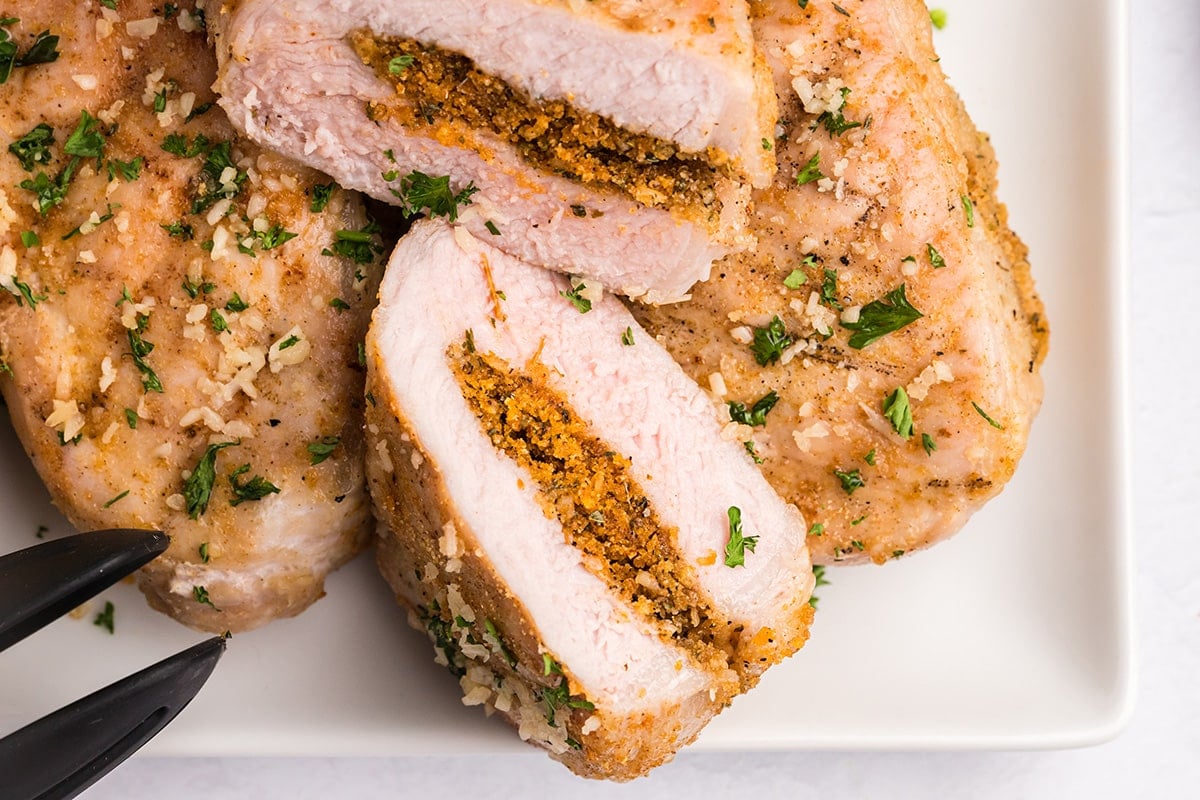 overhead shot of tray of grilled stuffed pork chops cut in half