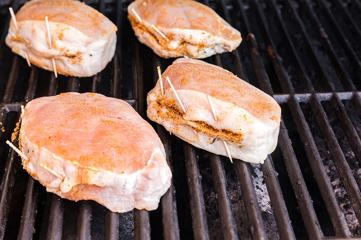 angled shot of stuffed pork chops cooking on grill