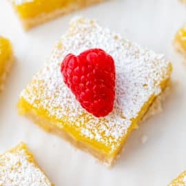 angled shot of lemon bar slice topped with raspberry