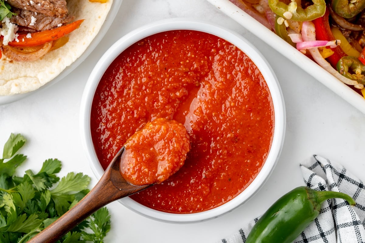 wooden spoon in bowl of ranchero sauce