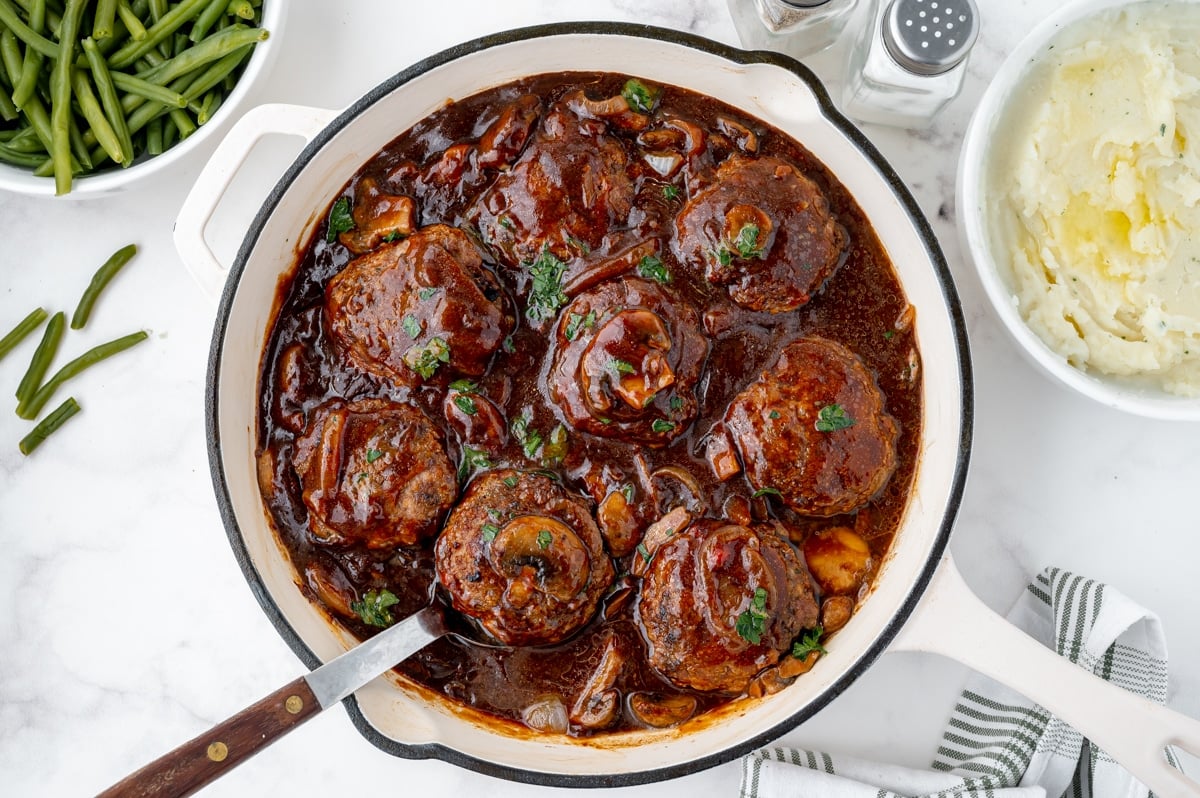 serving spoon in skillet of salisbury steaks