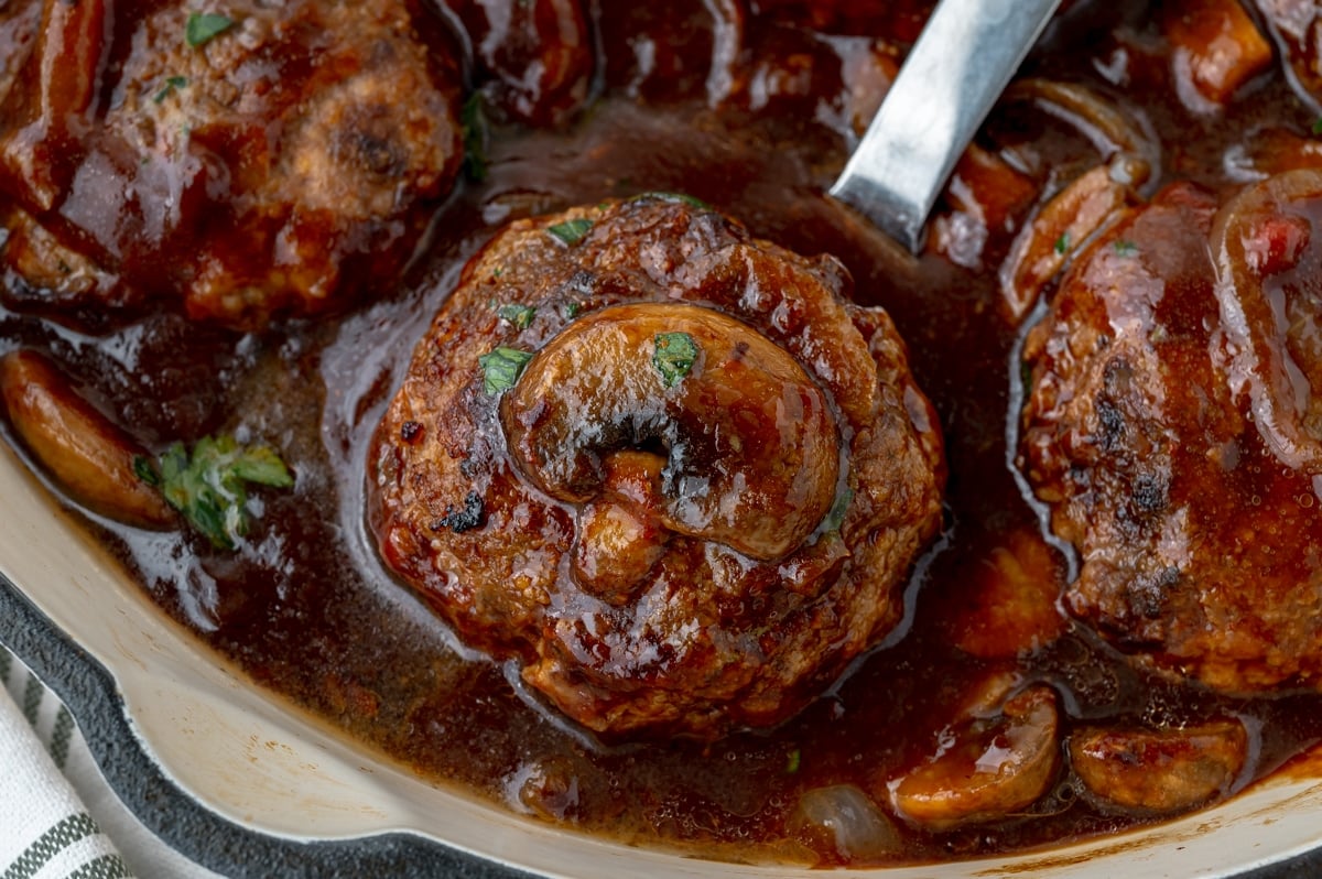 close up shot of mushroom on salisbury steak in skillet