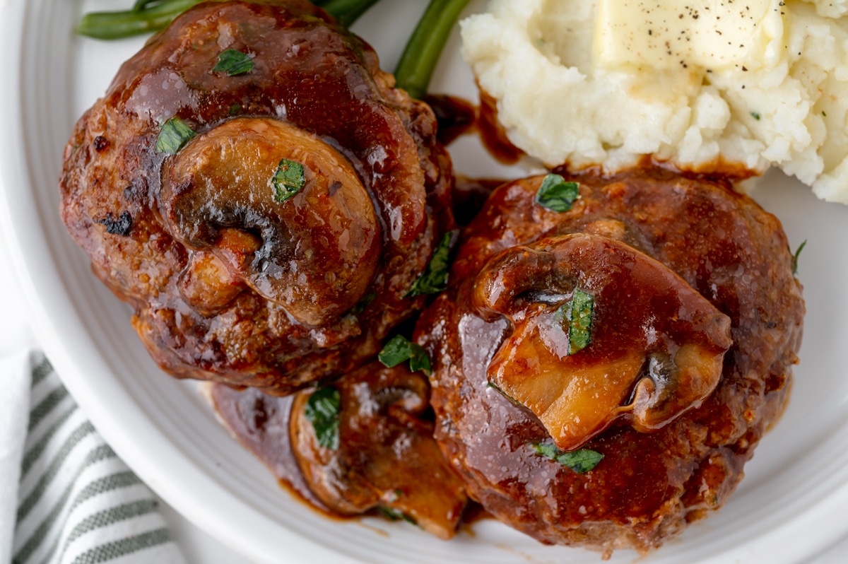 two salisbury steaks on a plate with potatoes