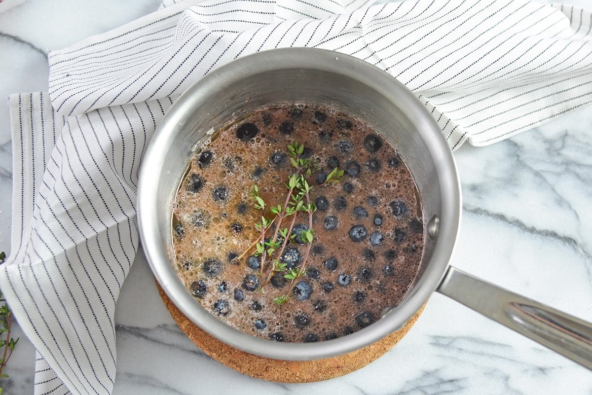 making a blueberry balsamic sauce with fresh thyme in a saucepan