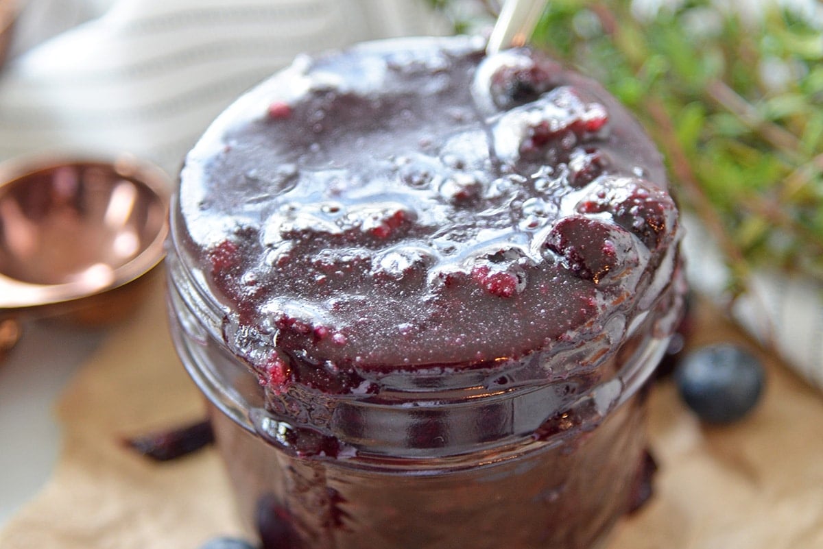 close up of shiny blueberry reduction in a small glass jar 