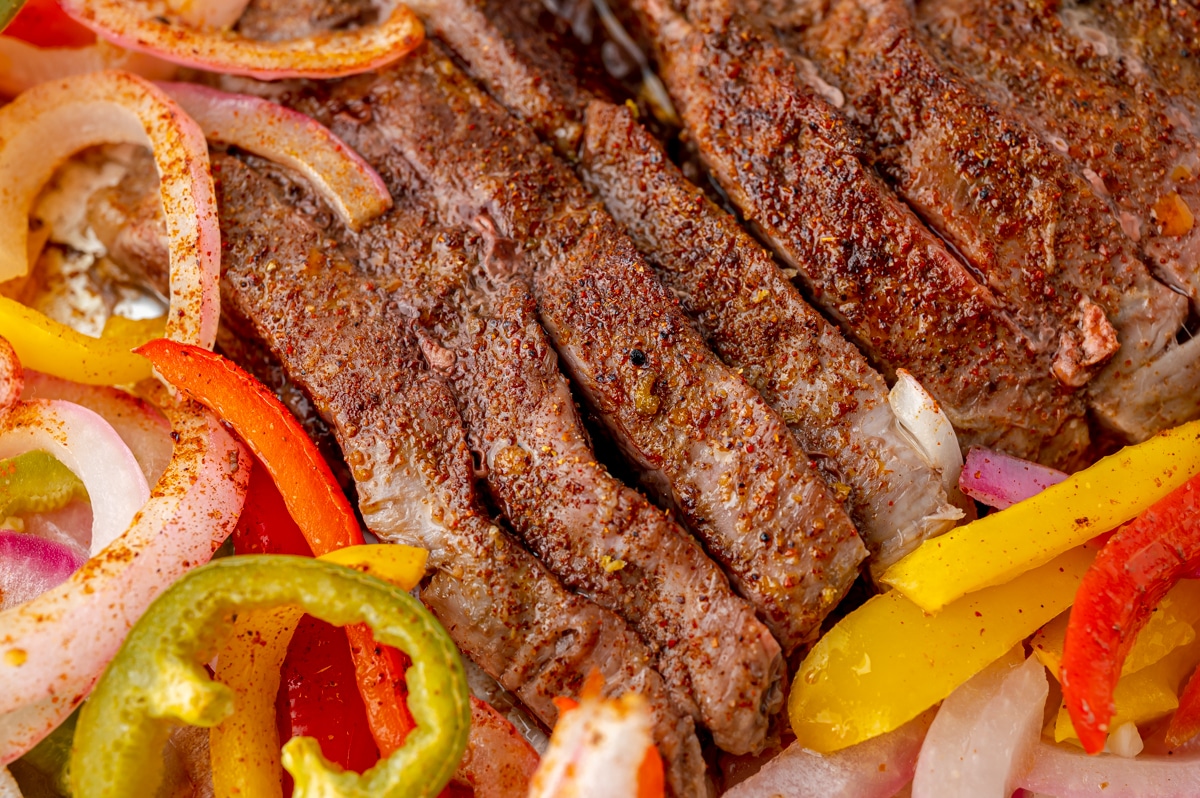 angled shot of sliced steak on a sheet pan with veggies