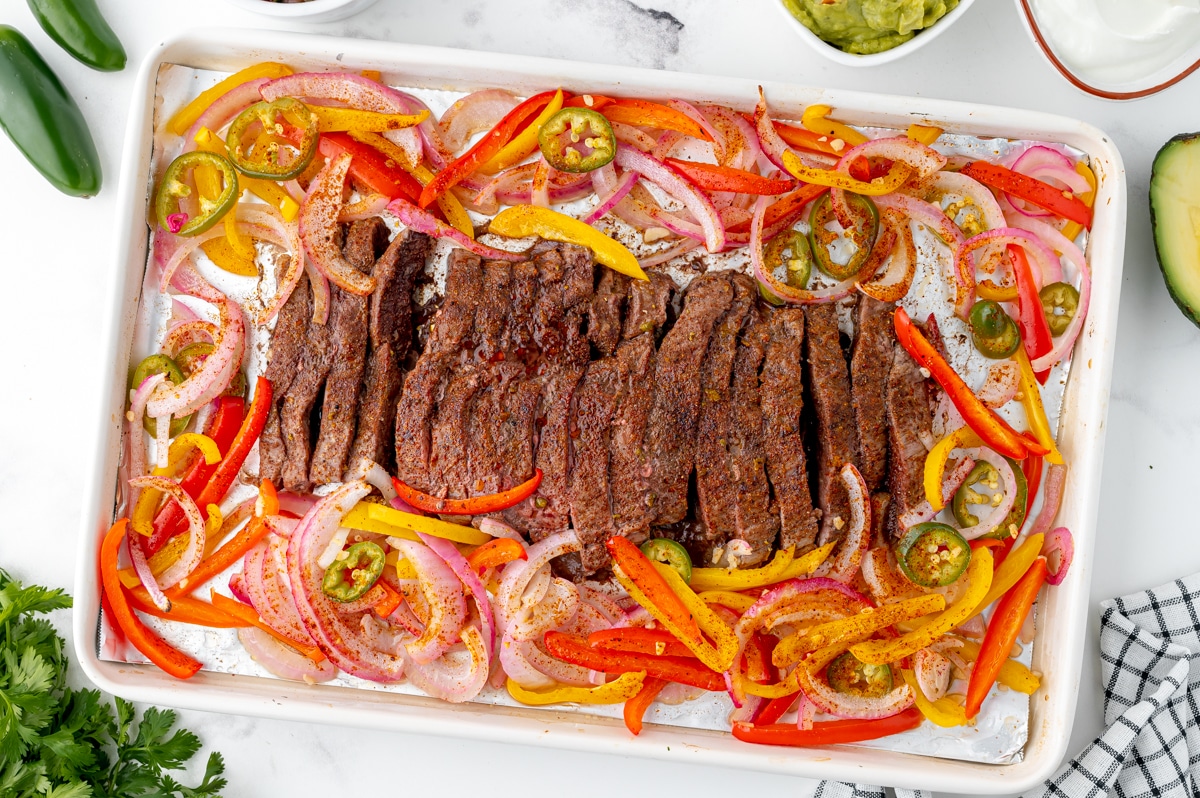 overhead shot of baked steak fajitas on a sheet pan