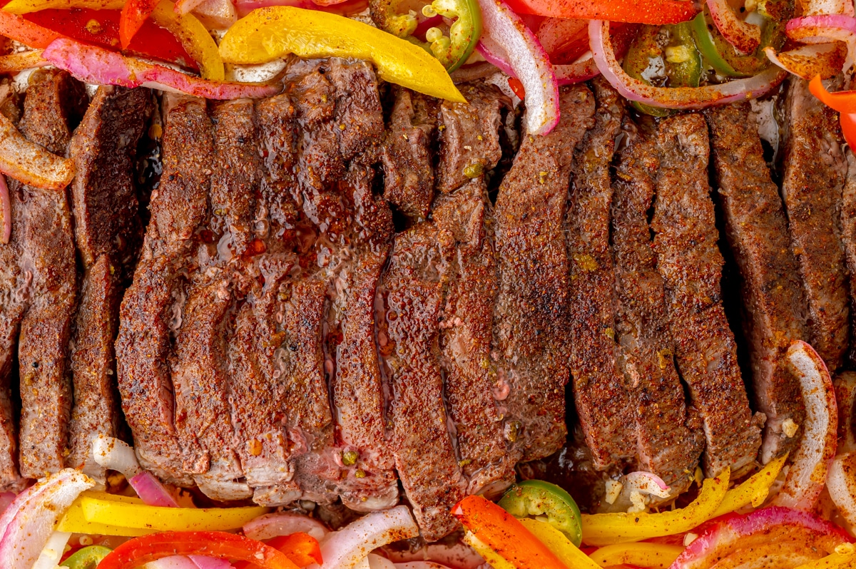 close up of sliced steak on a sheet pan with veggies