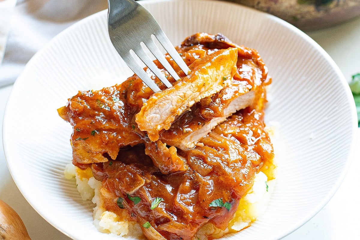 fork digging into bite of smothered pork chops