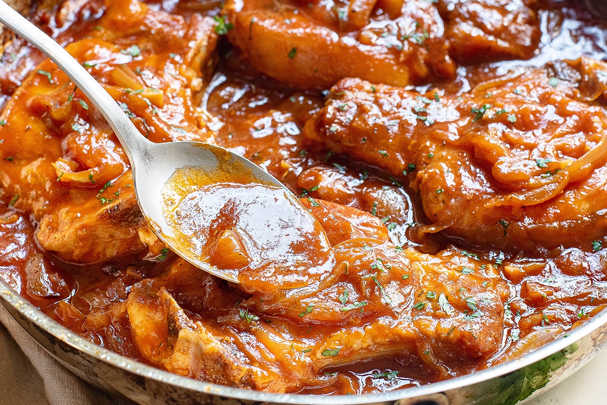 spoon in pan of smothered pork chops