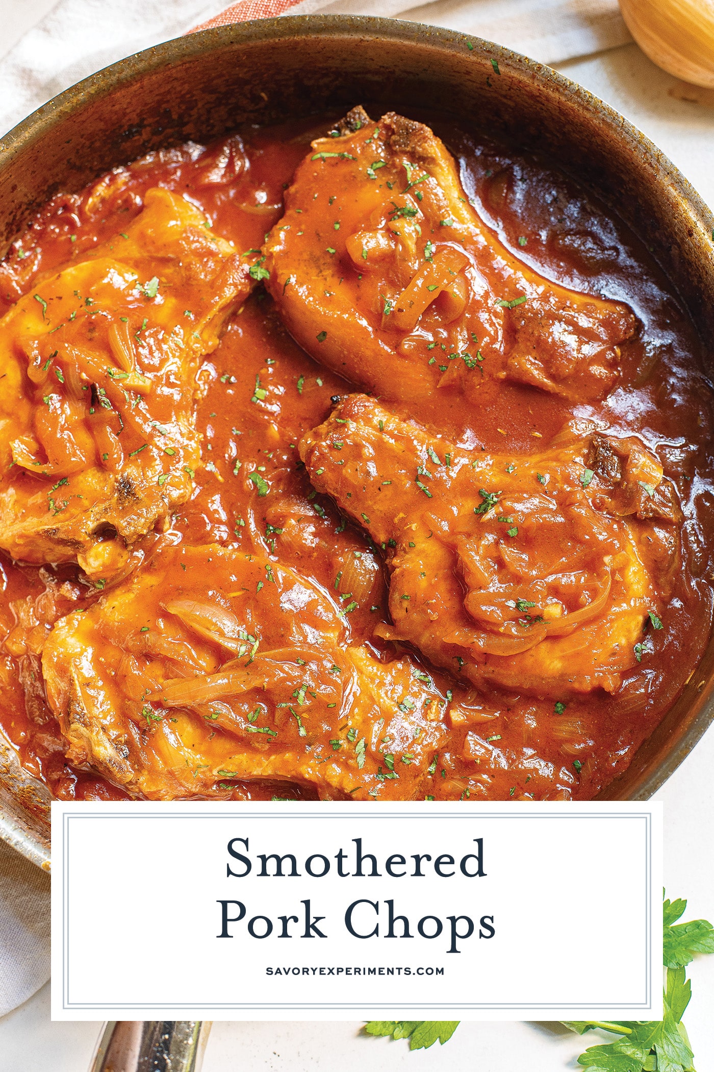 overhead shot of smothered pork chops in a pan with text overlay for pinterest