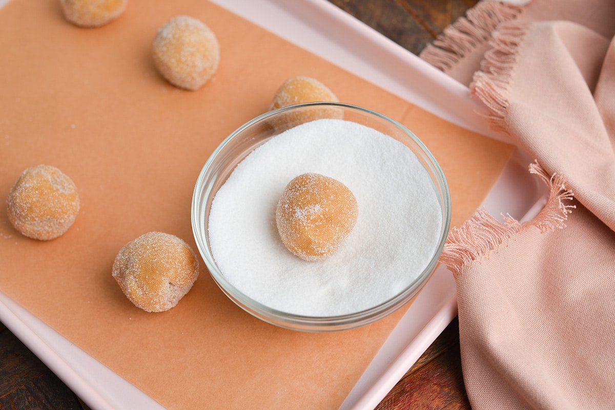 angled shot of snickerdoodle cookie ball rolling in sugar