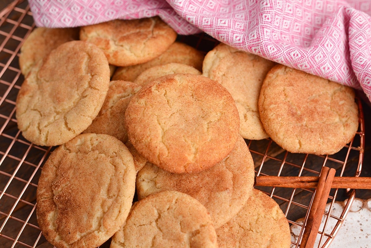 angled shot of pile of snickerdoodle cookies on a cooling rack