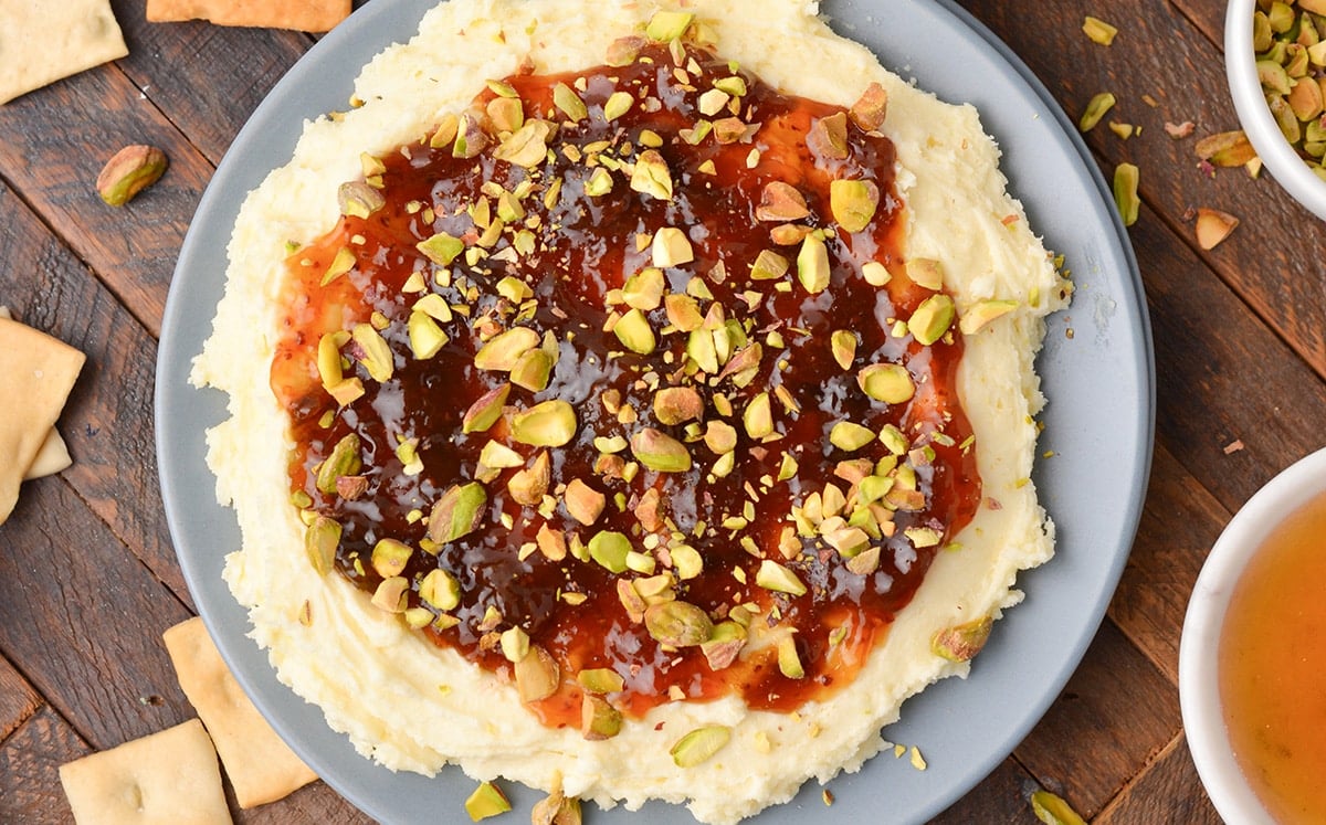 close up overhead shot of brie dip topped with jam and pistachios