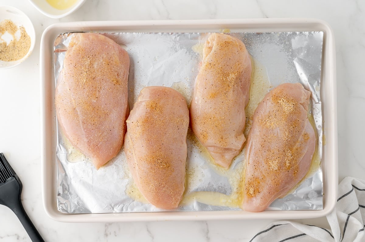 raw chicken on pan with seasonings