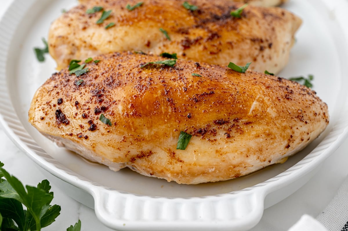 angled shot of juicy baked chicken breasts on a tray