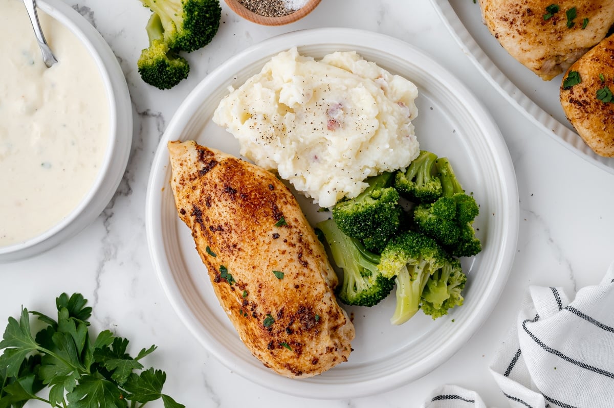 overhead shot of plate of baked chicken breast with broccoli and potatoes