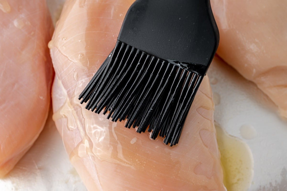 brushing oil onto raw chicken