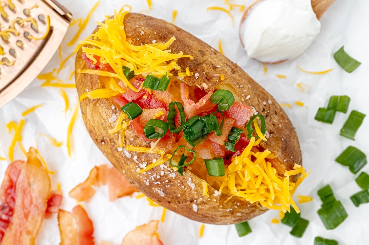 overhead shot of baked potato in oven topped with bacon and cheese