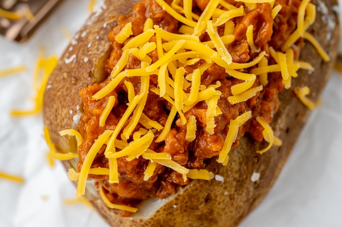 close up of baked potato topped with chili and cheese