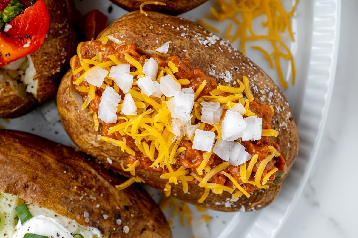 overhead shot of baked potato topped with chili, cheese and onions