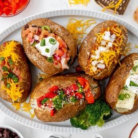 overhead shot of baked potatoes with different toppings on a tray