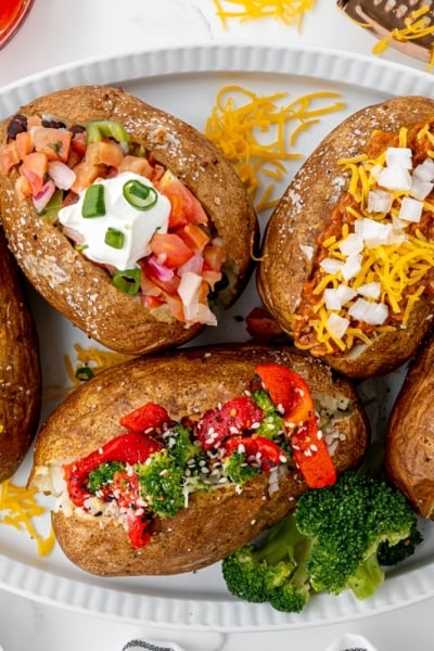 overhead shot of baked potatoes with different toppings on a tray